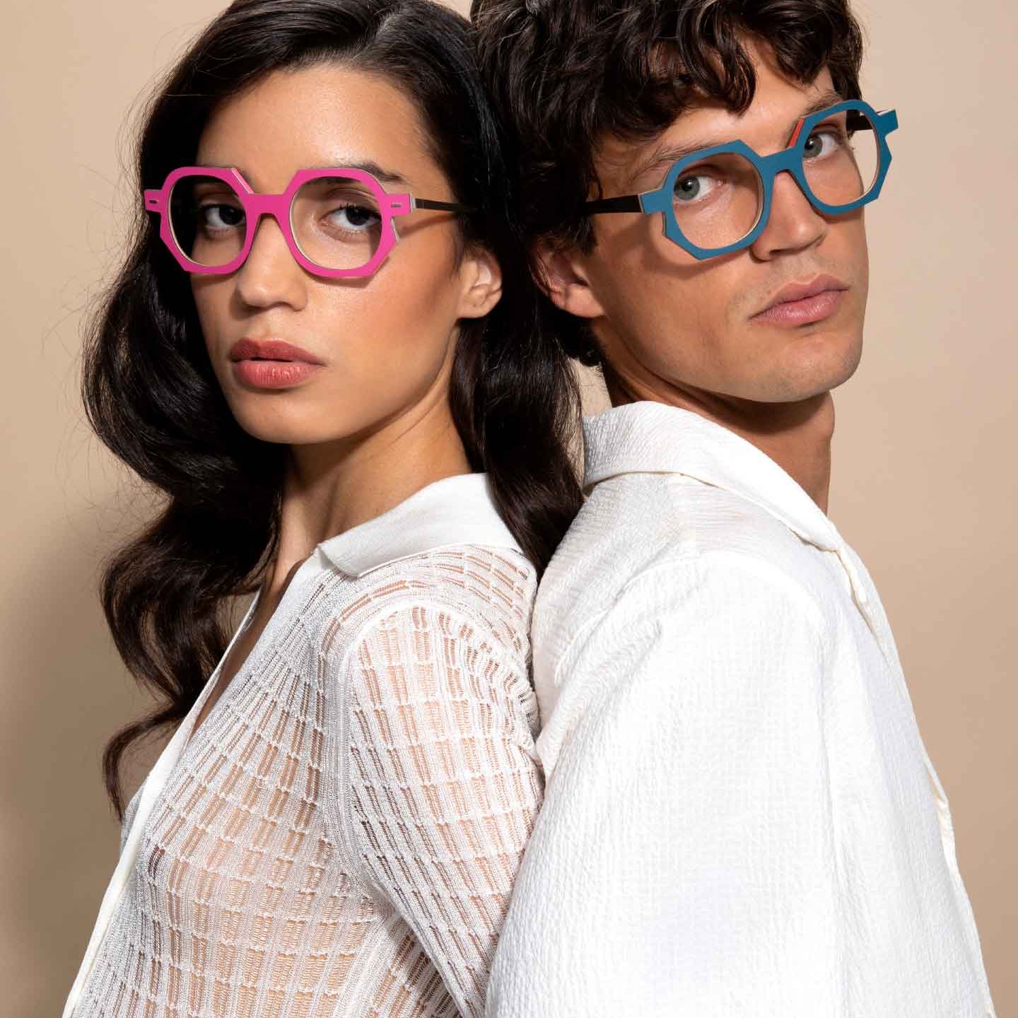 Two people wearing colorful glasses against a beige background