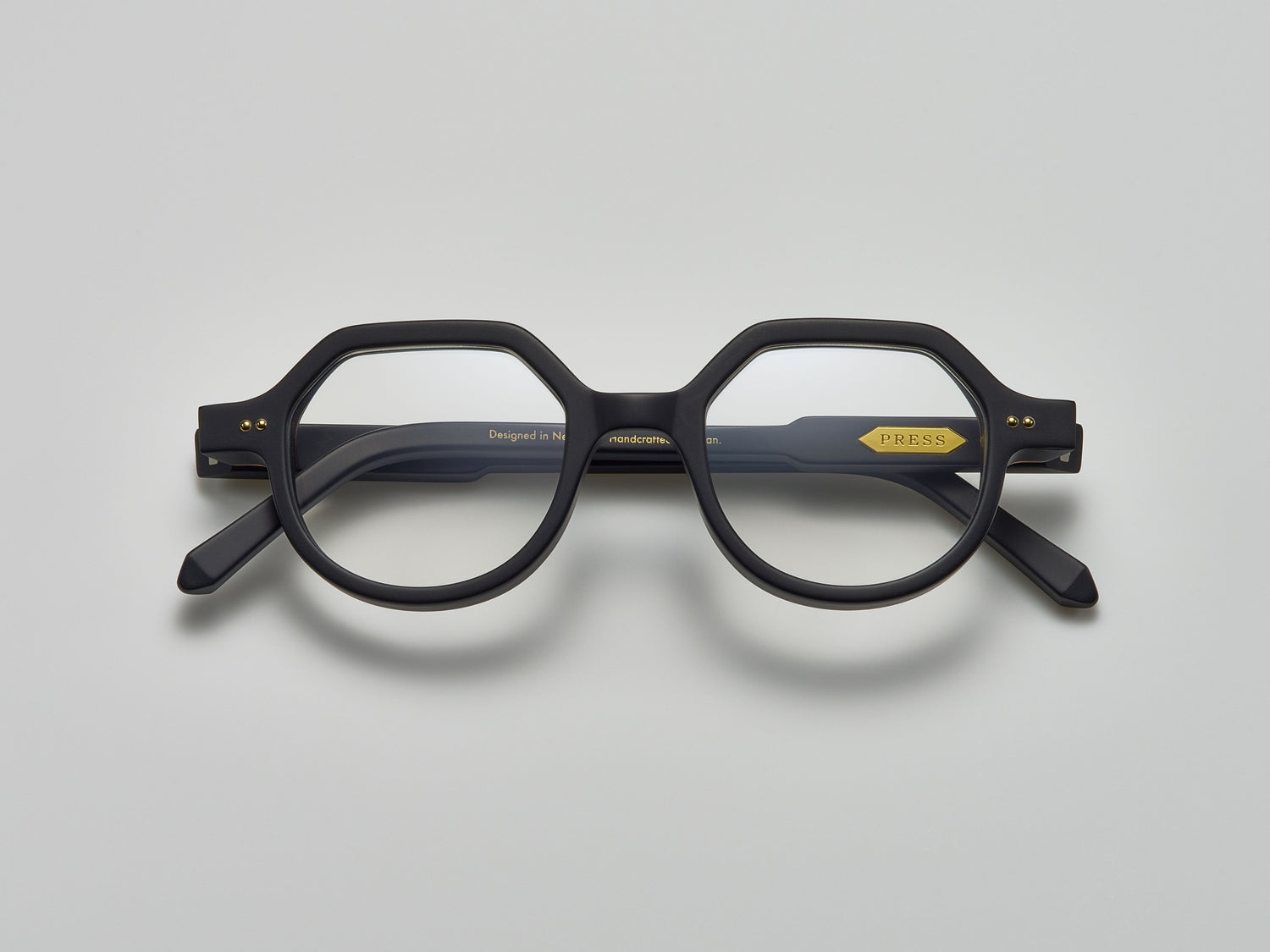 Mate black acetate eyeglasses with round and subtly geometric frames, featuring the brand name "PRESS" on the temple, by Yosemite Eyewear