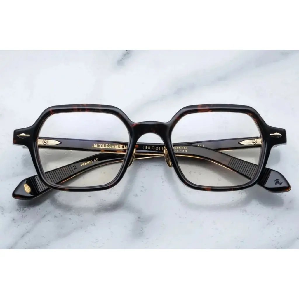 A pair of hexagonal full frame optical glasses with titanium nose pads and wirecores, displayed on a marble surface.