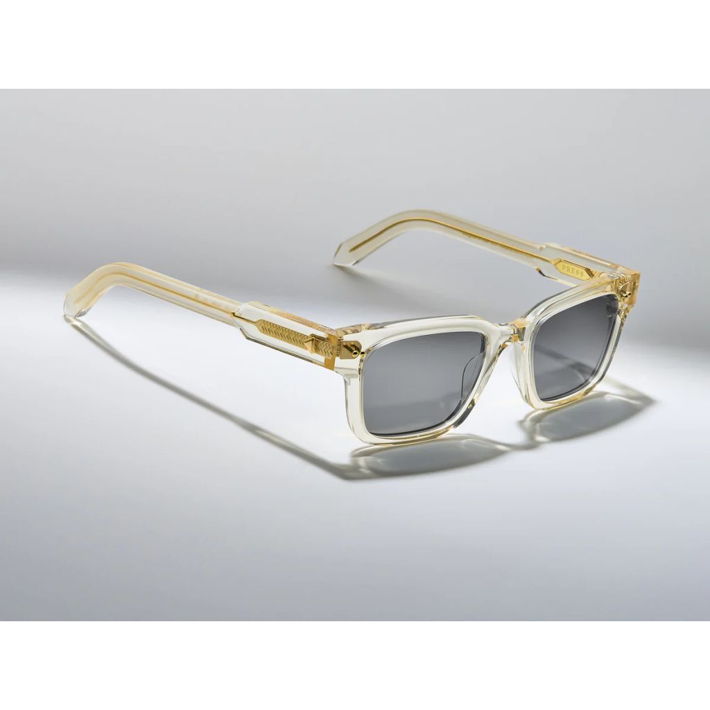 Sunglasses with gold frame and clear arms on a gray background