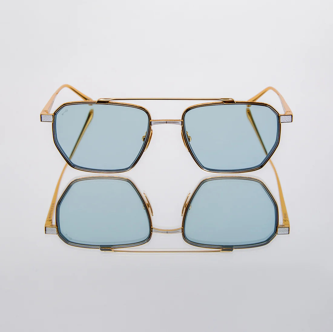 Leisure Society sunglasses with gold frame and blue lenses on a light gray background